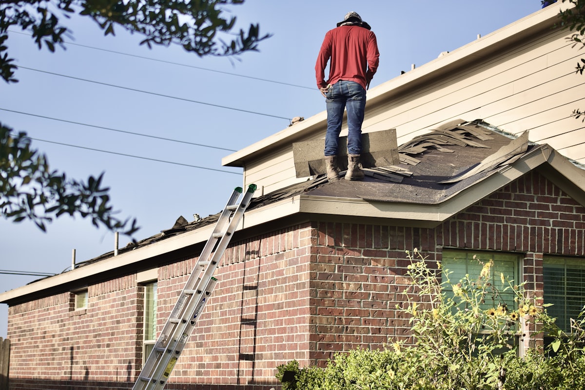 Roofer tearing off old shingles during a roof replacement